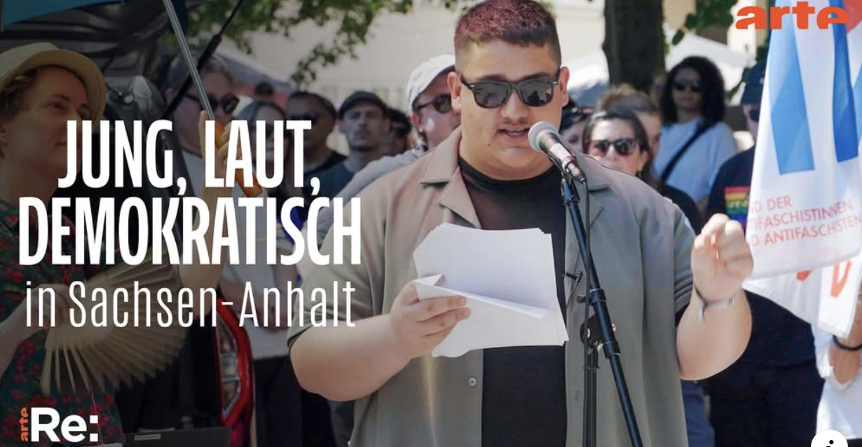 jung laut demokratisch. Max hält eine Redem am Mikrofon.